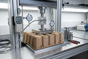 Molded pulp tray undergoing compression testing on engineering equipment